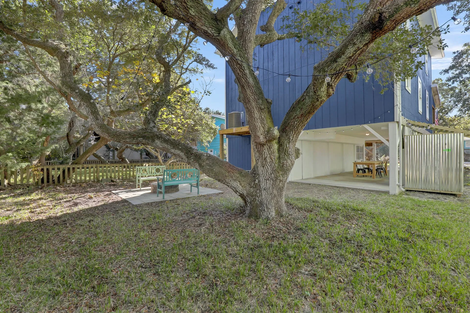 Backyard live oak with the under-house dining area beyond