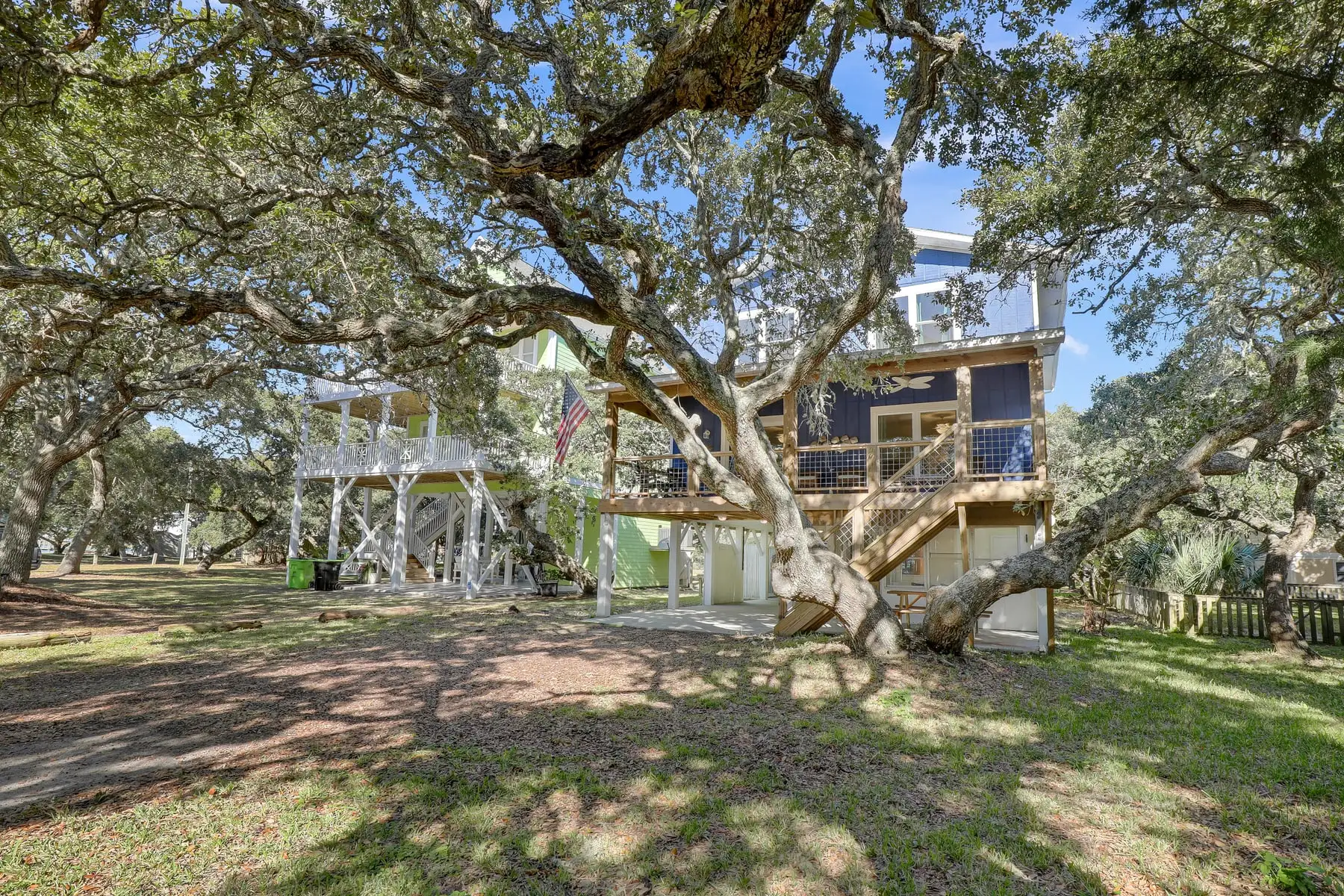 The blue Sound to Sea beach house framed by a live oak tree on Topsail Island